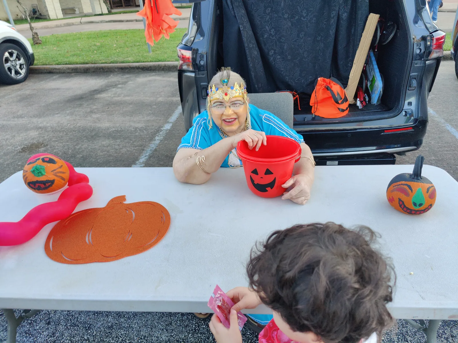 A volunteer in costume hands out candy from a decorated car trunk at a church trunk-or-treat in Houston.