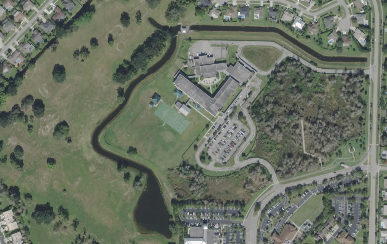 Elbridge Gale Elementary on Royal Fern Drive in Wellington from the air, with open land and a canal around the campus