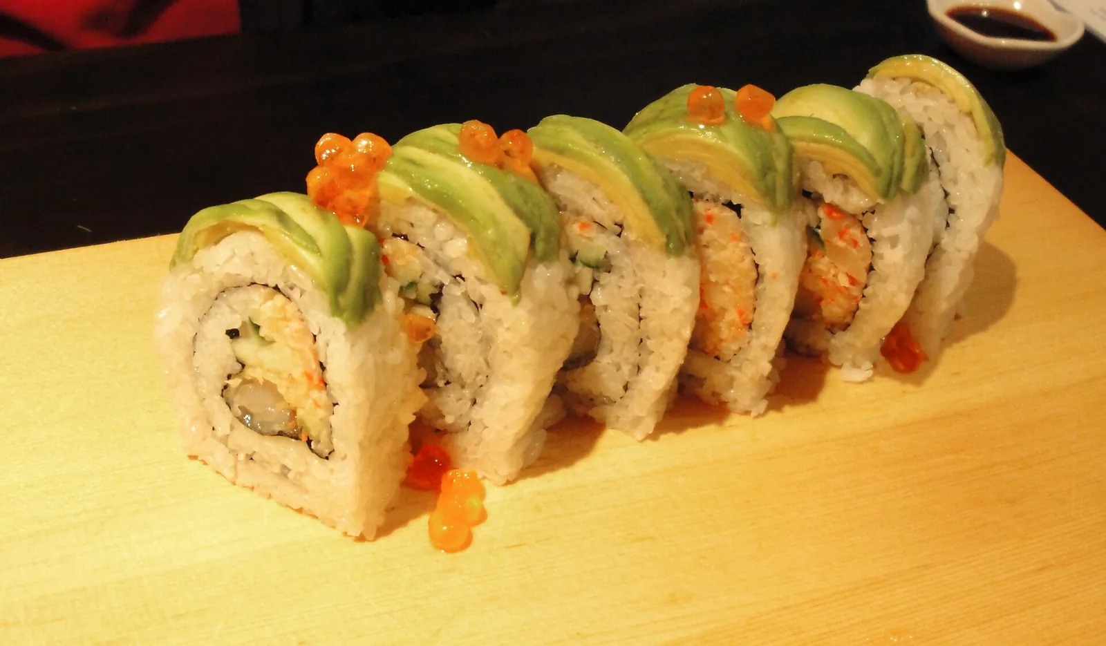 A sushi roll topped with avocado and salmon roe. The photo was not taken at a Wellington restaurant.