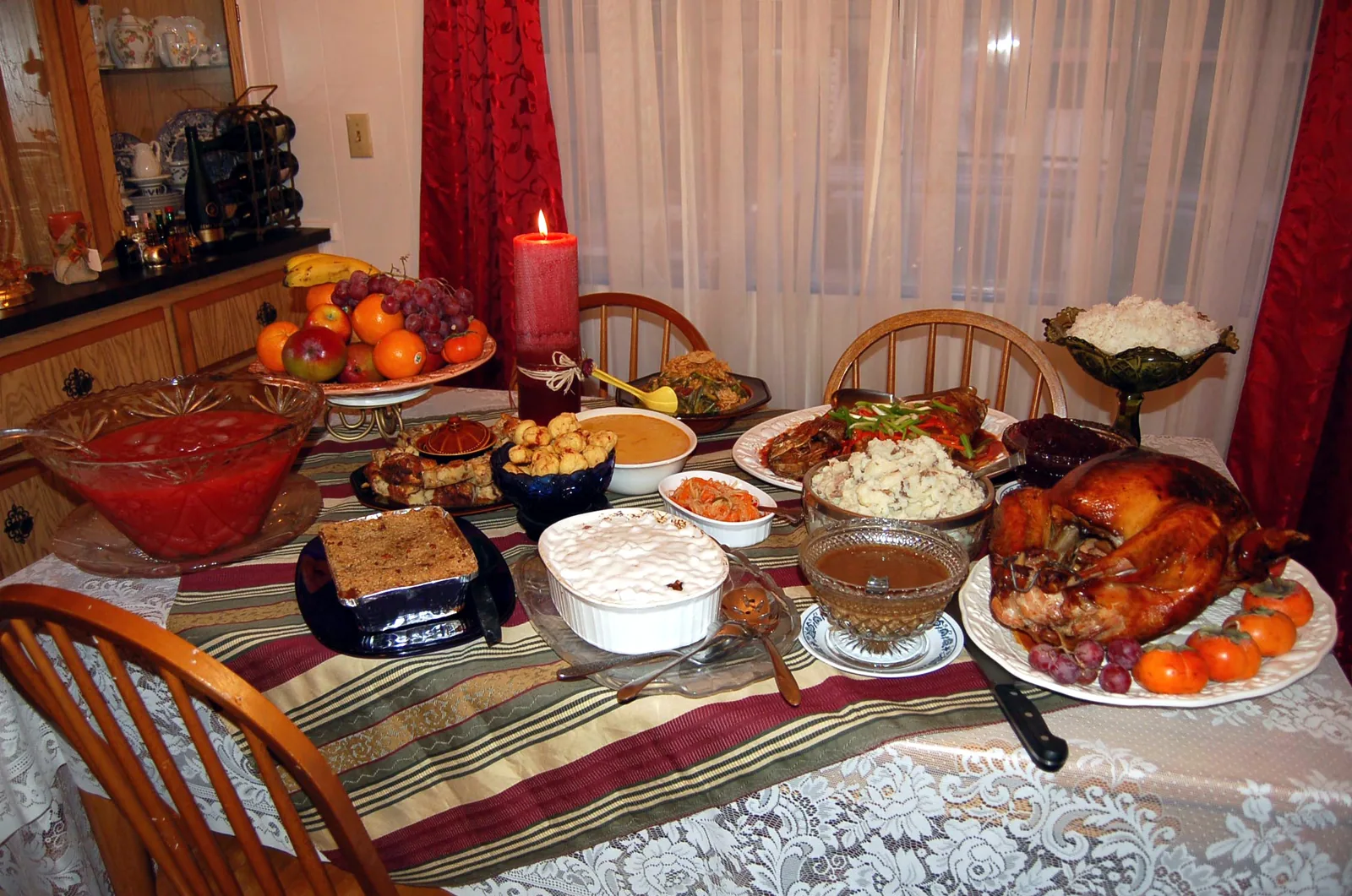 A roast turkey with gravy, cranberry sauce and side dishes laid out for a family Thanksgiving dinner.
