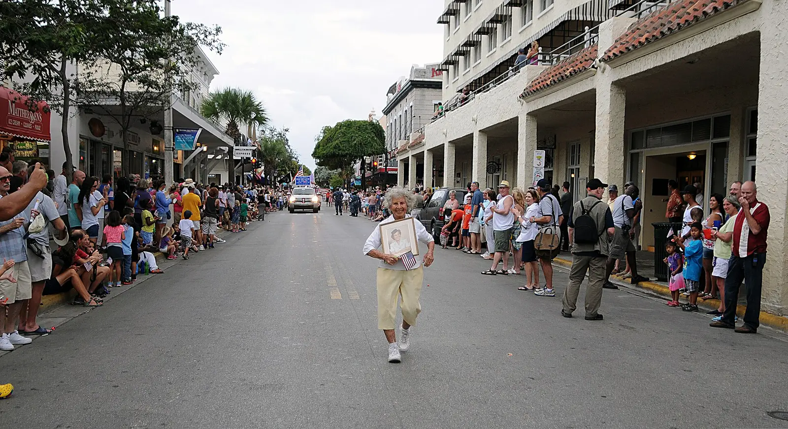 A veteran carries a portrait of herself in uniform along Duval Street during the Veterans Day parade in Key West, Fla.