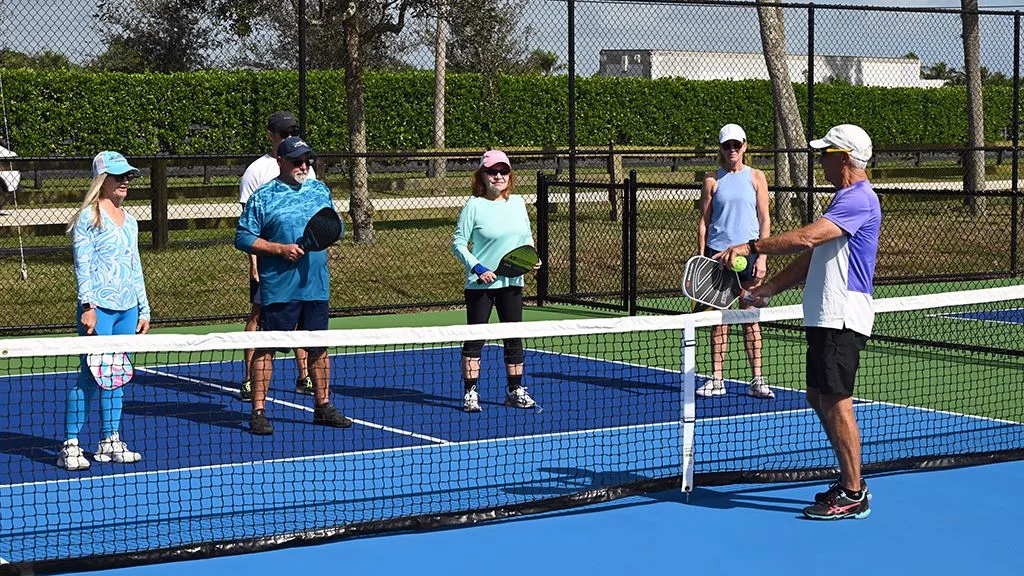 A coach shows a group of players how to hold the paddle at a Wellington pickleball clinic.